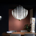 Spherical wire pendant light glowing against a dark backdrop