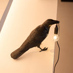 Raven sculpture lamp detail with warm filament glow