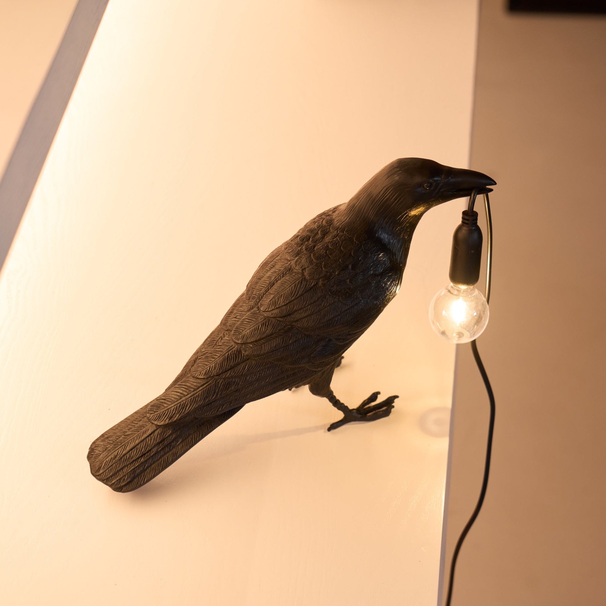 Raven sculpture lamp detail with warm filament glow