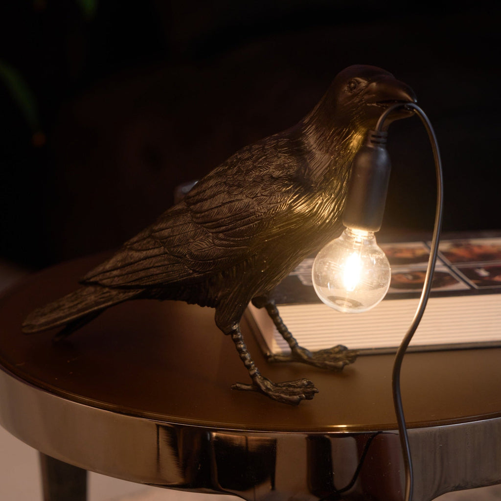 White raven table lamp glowing on a desktop