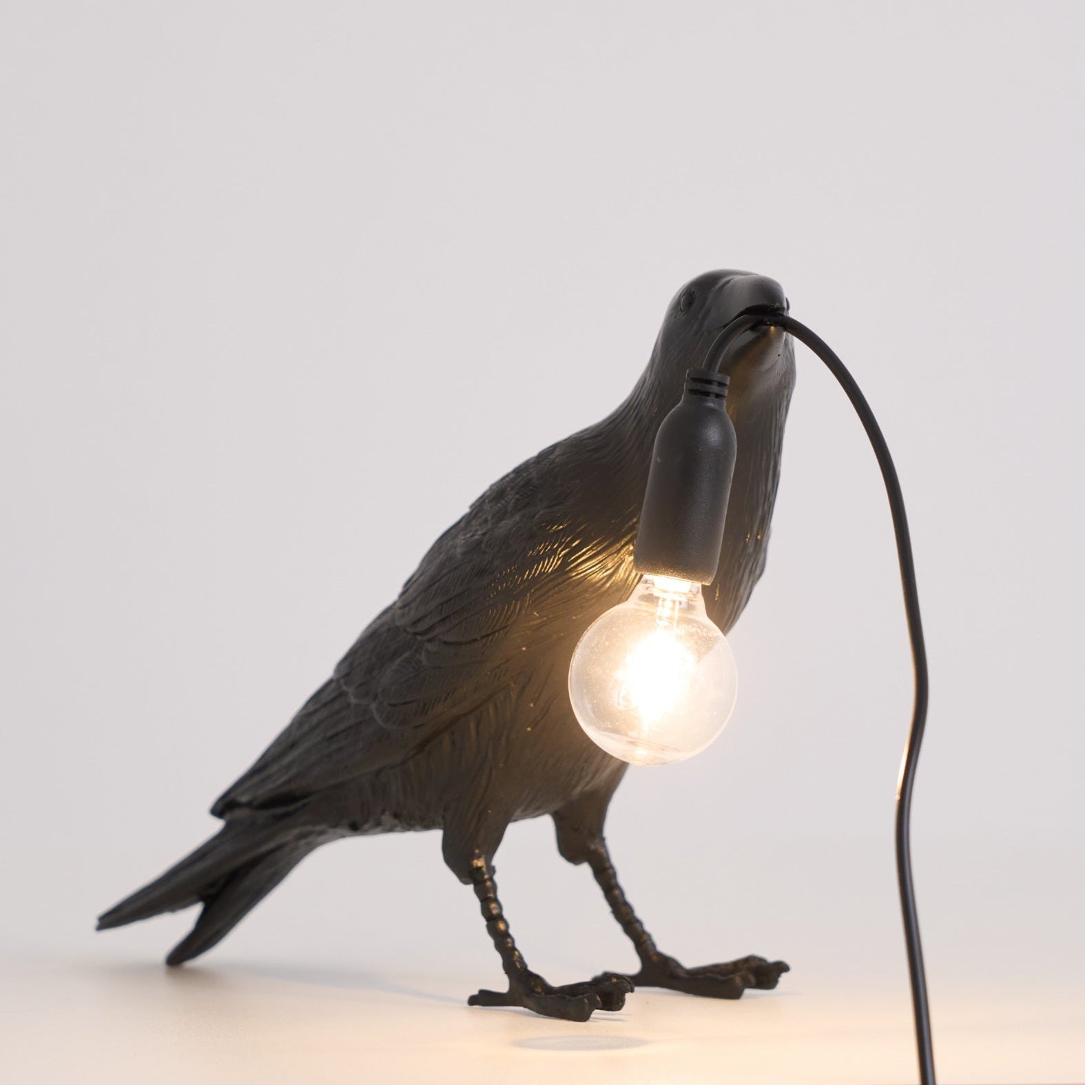 White raven lamp perched with an exposed filament bulb