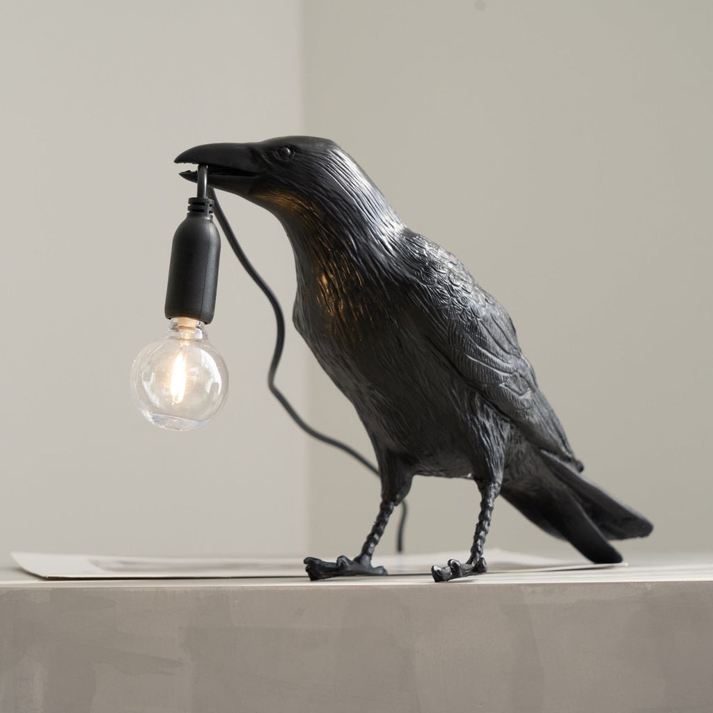 White raven resin lamp holding an Edison bulb in its beak