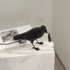 Raven table lamp in perched pose with glowing bulb
