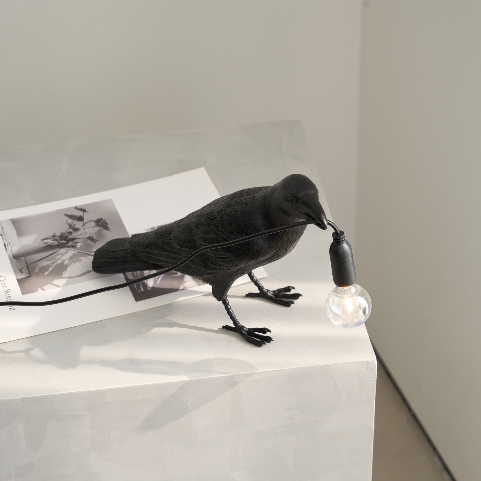 Raven table lamp in perched pose with glowing bulb