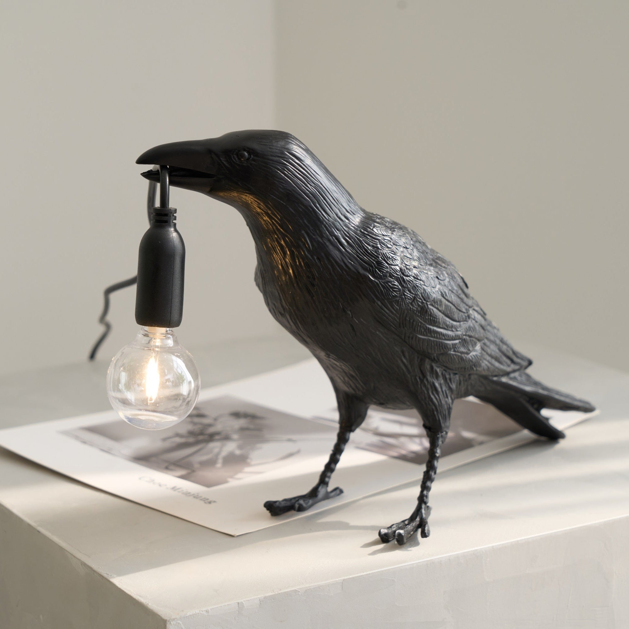 White raven resin lamp in resting pose with warm light