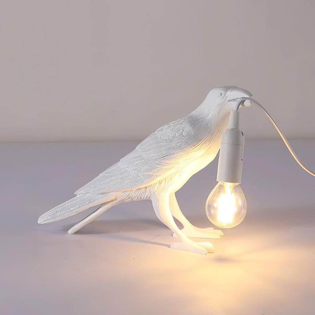 Raven table lamp casting amber light on a shelf