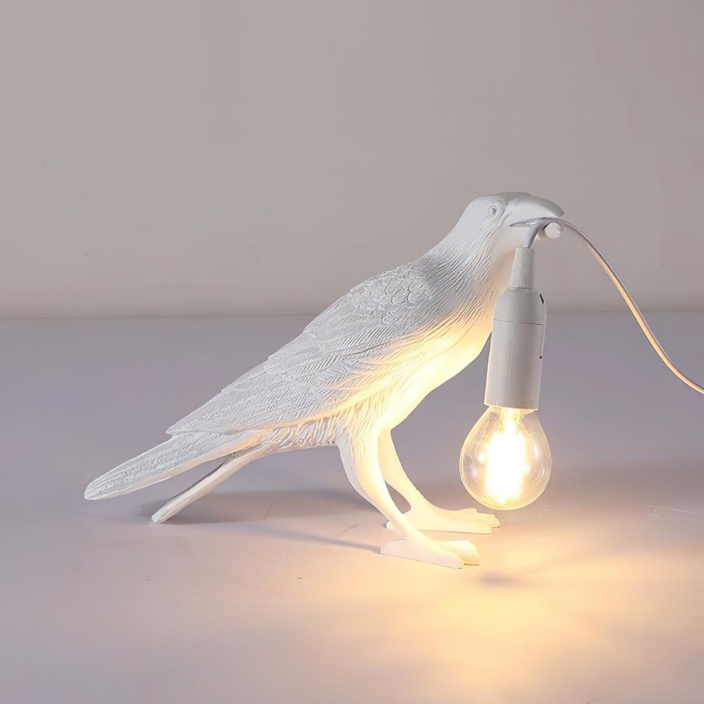 Raven table lamp casting amber light on a shelf