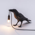 Black raven sculpture lamp with warm exposed filament bulb