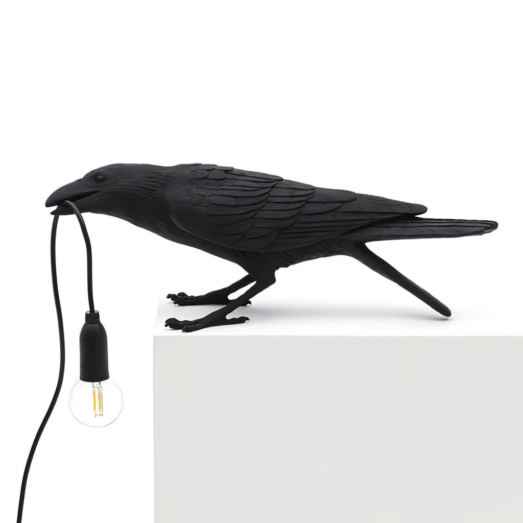 Resin raven table lamp holding a glowing Edison bulb in its beak