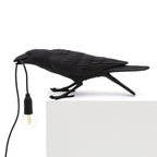 Resin raven table lamp holding a glowing Edison bulb in its beak