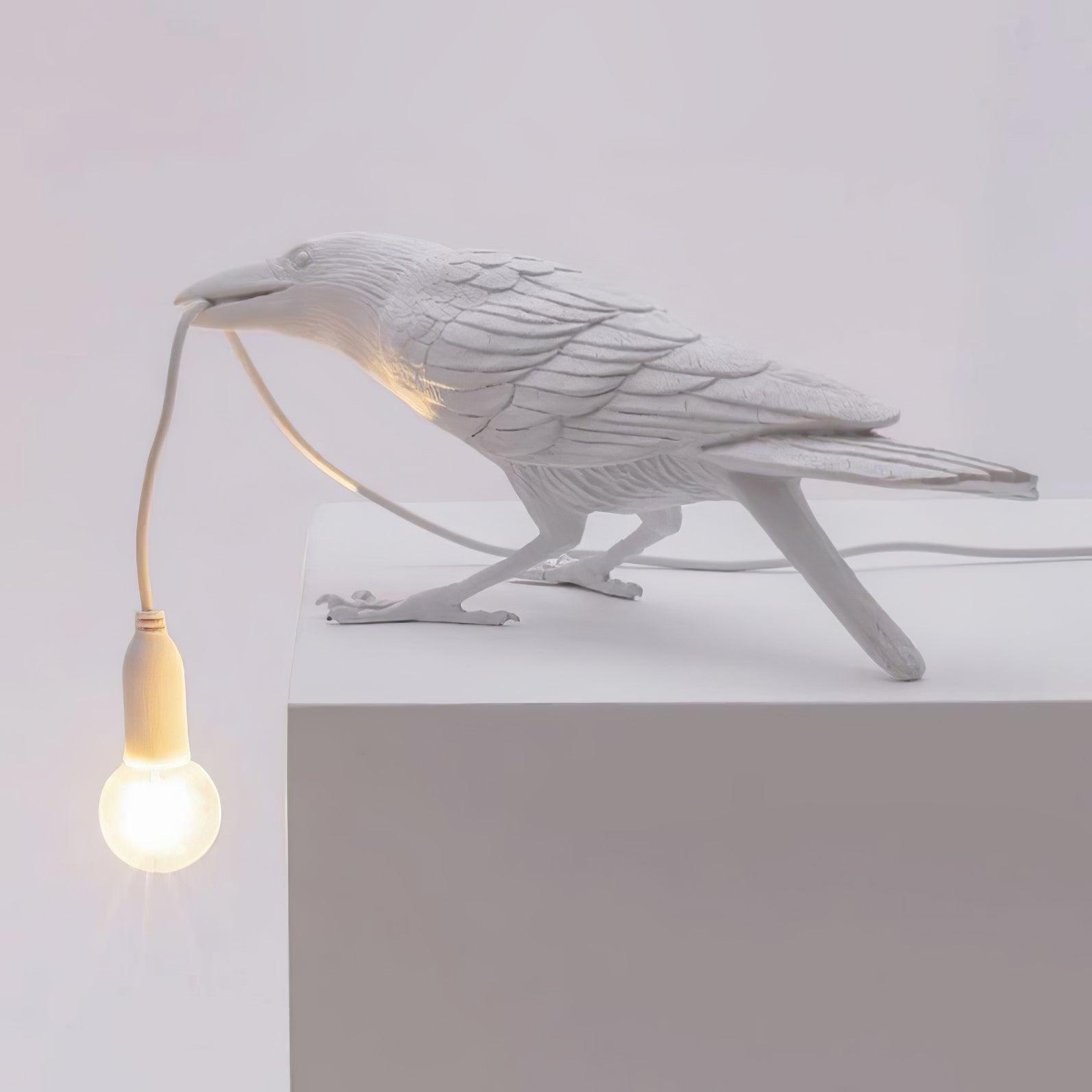 Raven table lamp lit on a dark side table