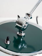 Close view of the green base disc and switch button on this Clérachic desk lamp's swivel joint.