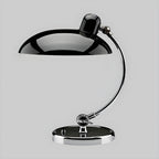 Set against a plain grey backdrop, this black Clérachic desk lamp shows its domed shade in profile.