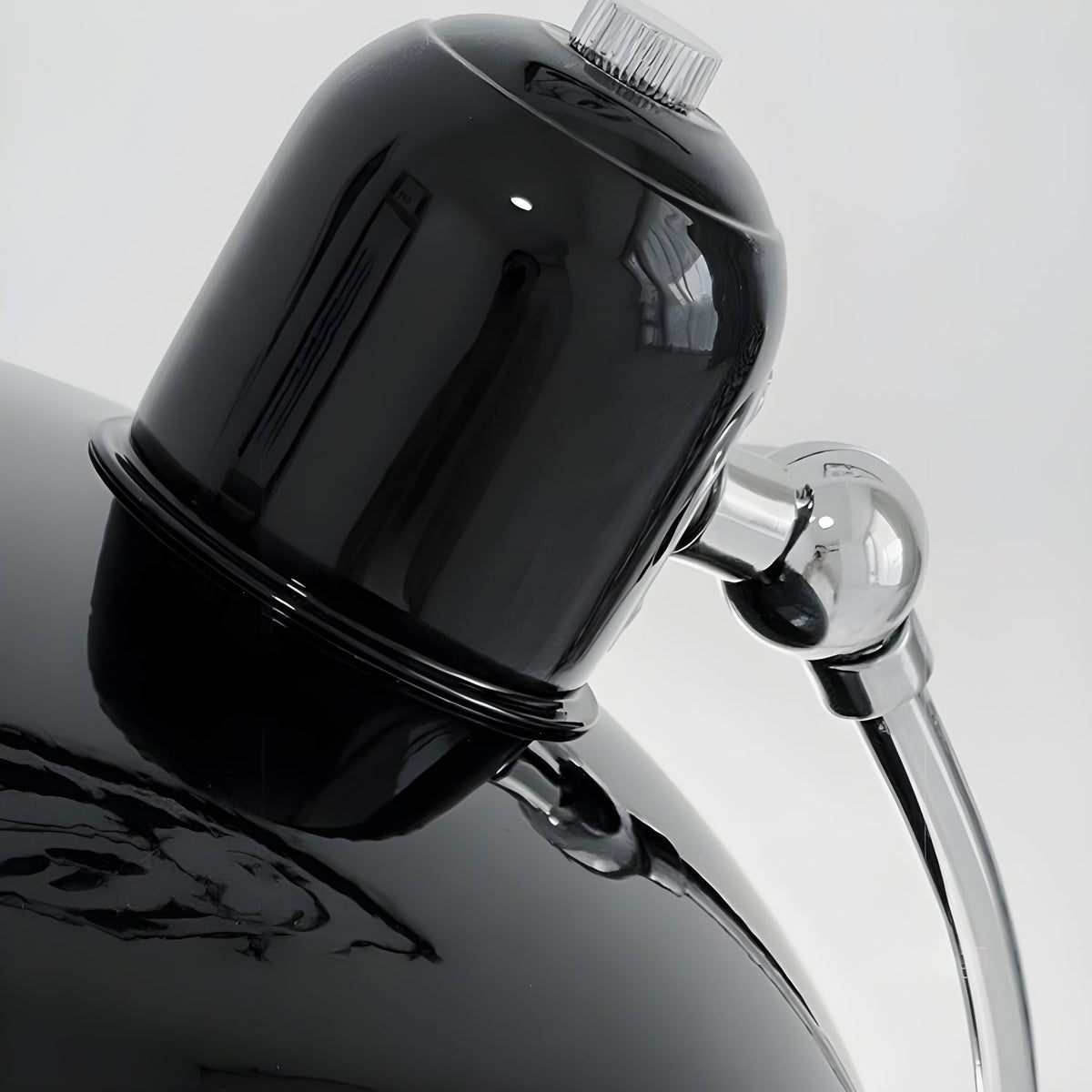 Close view of the glossy black dome shade and chrome joint on this Clérachic desk lamp.