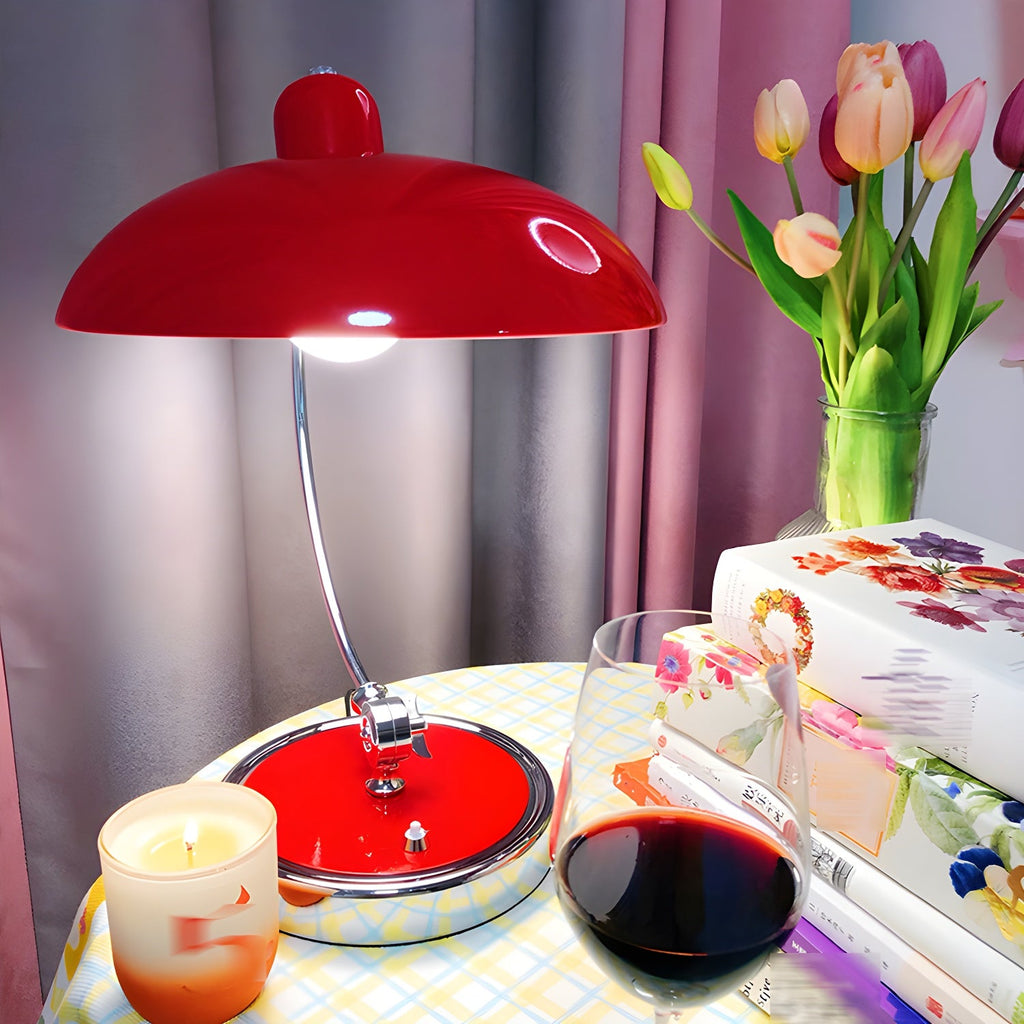 A red Clérachic desk lamp lit on a table set with tulips, a candle and a glass of wine.