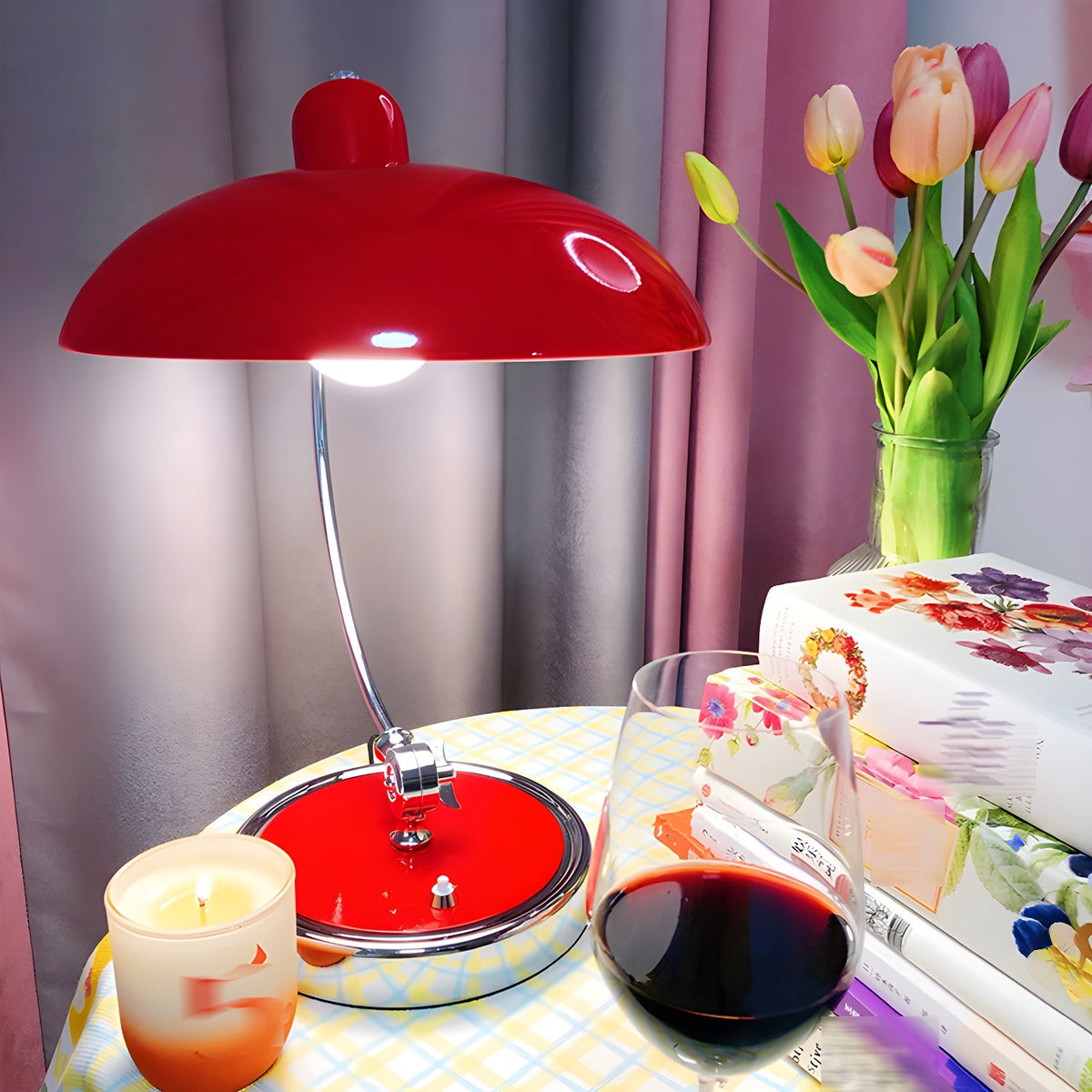 A red Clérachic desk lamp lit on a table set with tulips, a candle and a glass of wine.