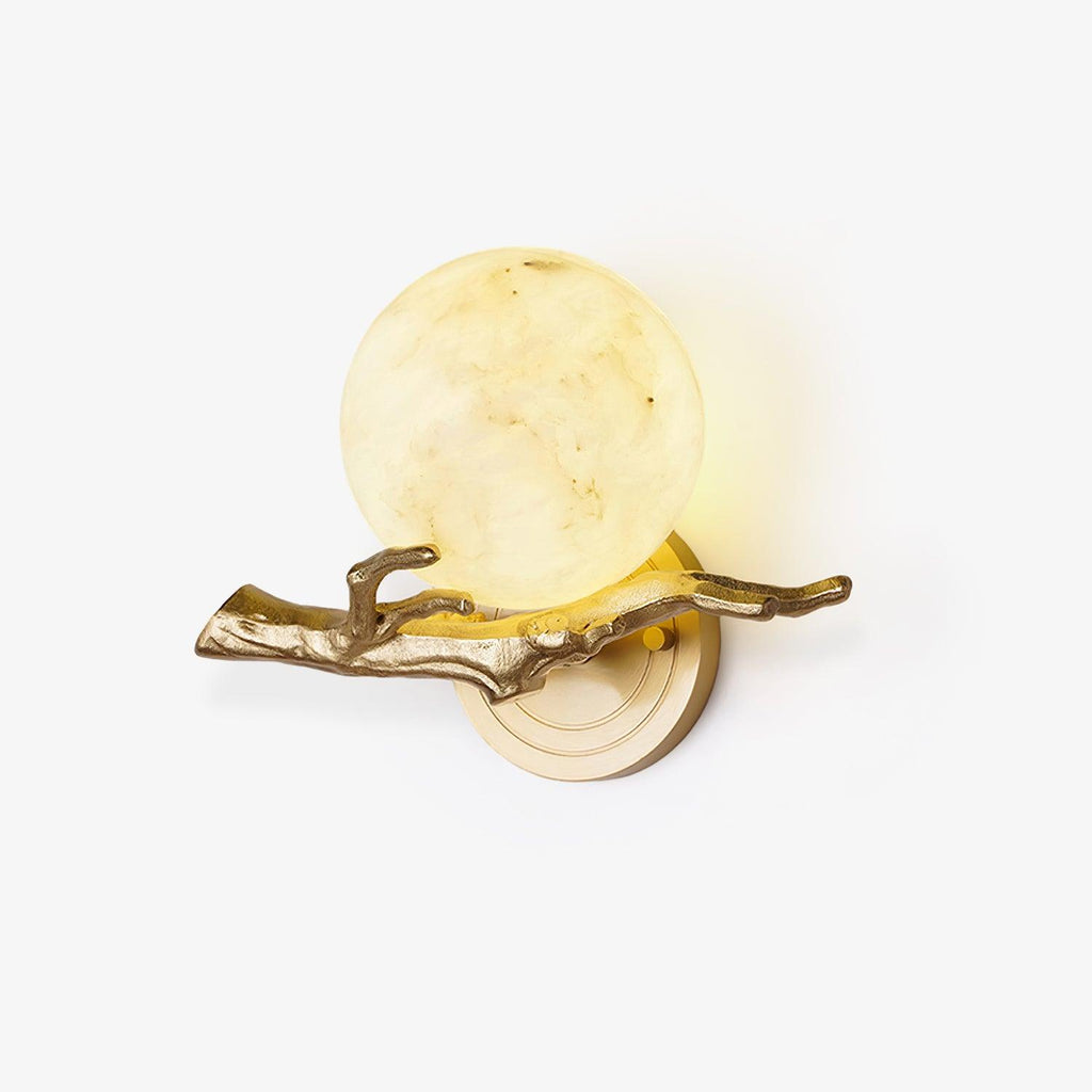 Clérachic brass wall light with a glowing round marble shade, shown straight on against a plain white studio background.