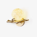 Clérachic brass wall light with a glowing round marble shade, shown straight on against a plain white studio background.