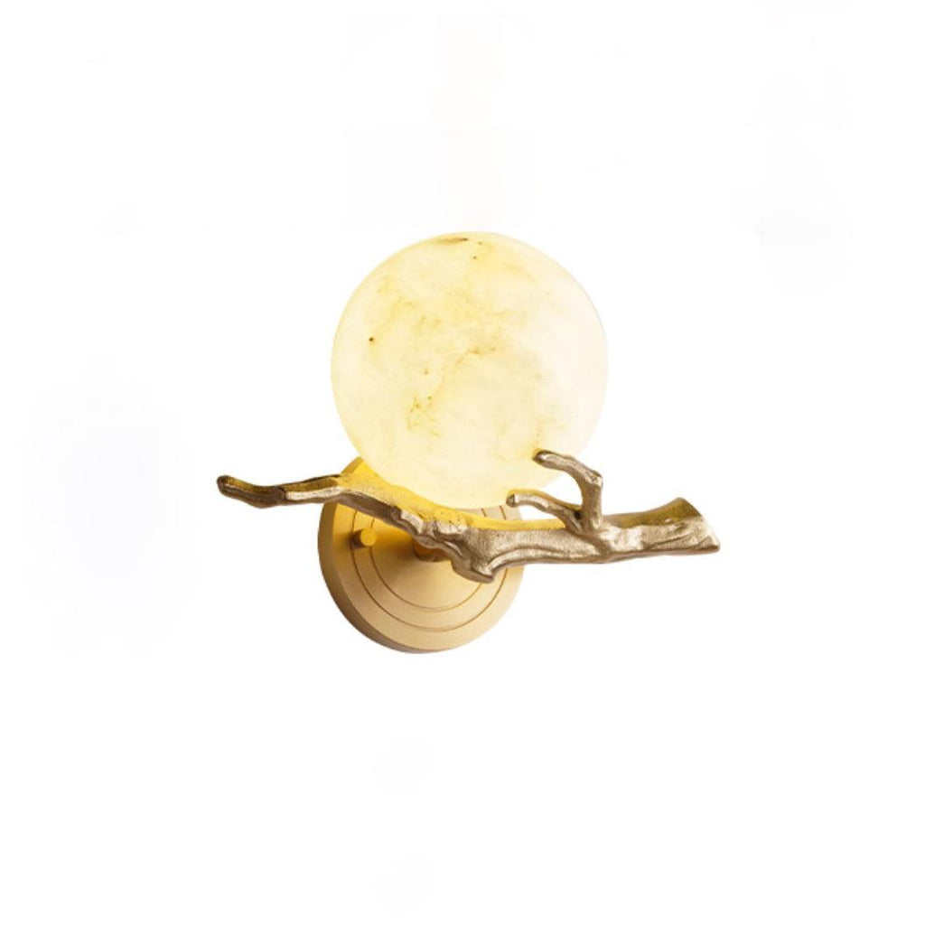 Studio shot of the lit Clérachic wall light on white, framed wide to show the full curve of the brass twig base.
