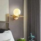 The lit Clérachic sconce is fixed beside a mirror reflecting a bronze horse figurine and a potted plant in a bedroom.