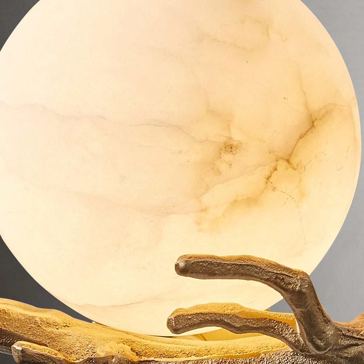 Extreme close-up of the marble shade's natural veining on the Clérachic sconce, lit from within with a warm glow.