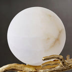 A cooler-toned close-up of the marble shade on the Clérachic sconce, showing subtle grey veining above the brass arm.