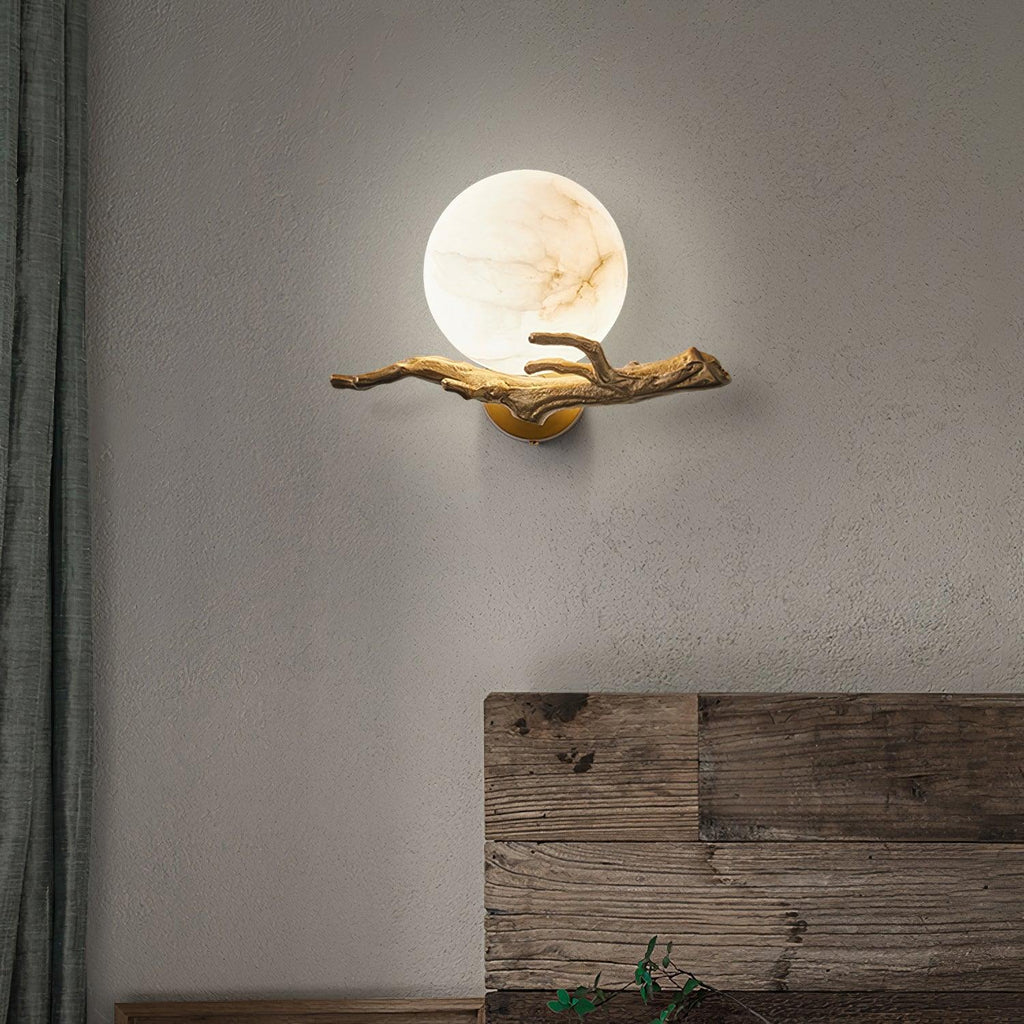 Mounted on a textured grey plaster wall, the Clérachic sconce glows beside a weathered plank of wood leaning nearby.