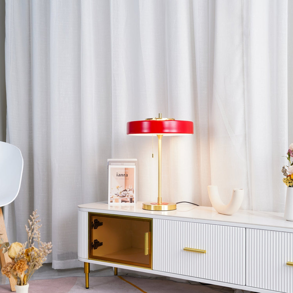 Spun metal table lamp with warm light on a shelf