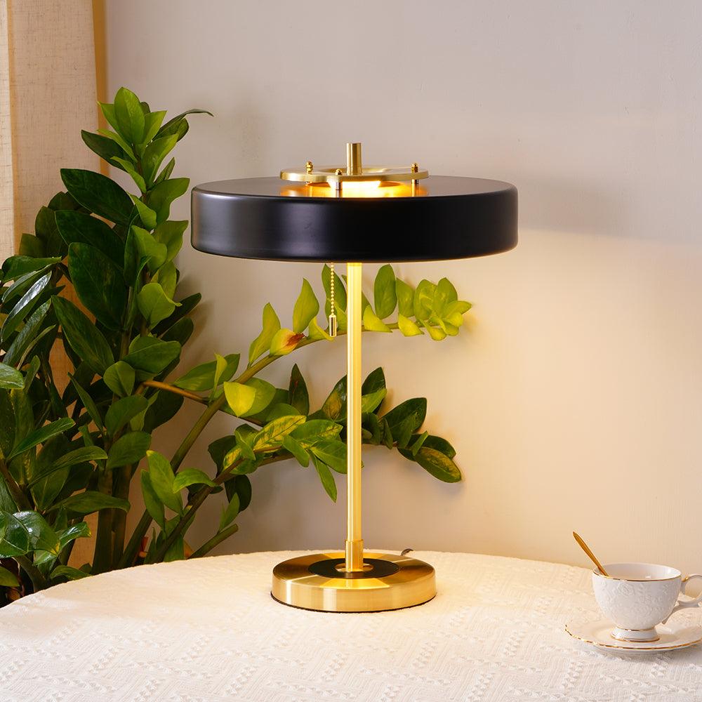 Revolve table lamp shade lit warmly on a console