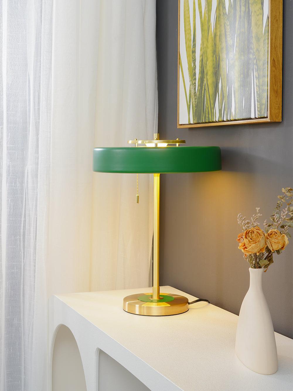 Spun metal table lamp glowing warm from its opal diffuser