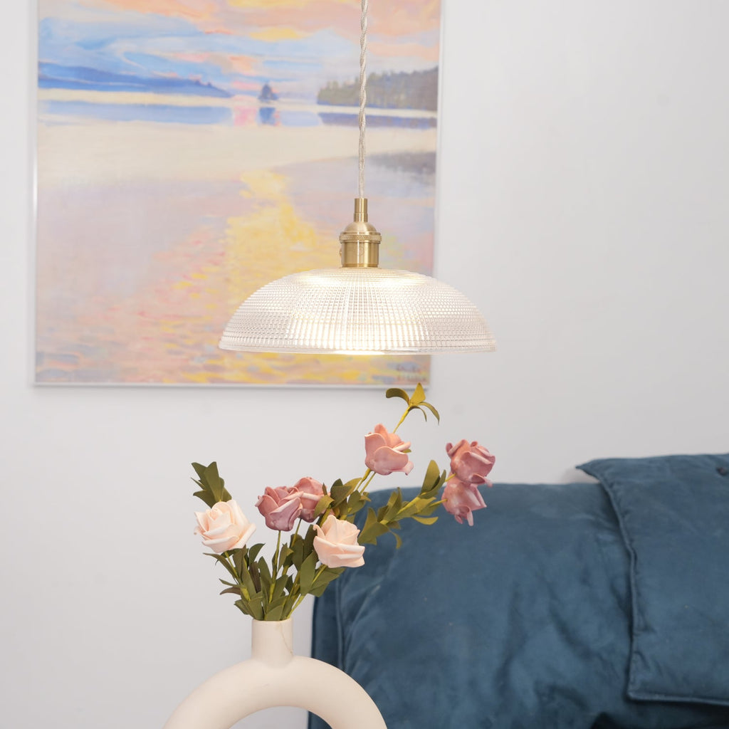 Unlit above a ring-shaped vase of pink roses, this Clérachic pendant hangs with a framed painting in the background.