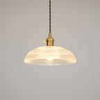 Lit against a plain off-white background, this Clérachic pendant's ribbed glass shade glows evenly around its brass fitting.