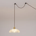 This Clérachic pendant is shown as a swag light, its cord looped between two wall hooks before dropping to the shade.