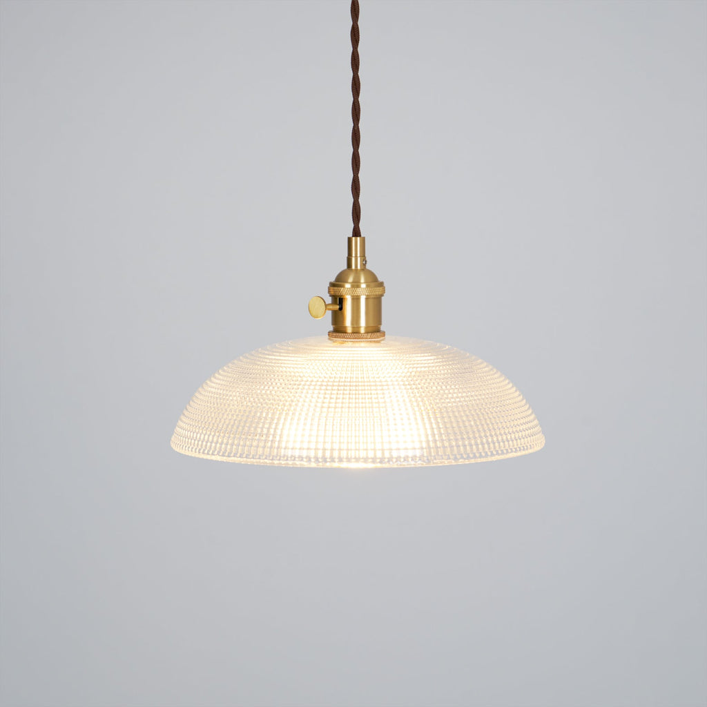 Lit against a plain grey background, this Clérachic pendant shows a dark twisted cord and brass fitting.