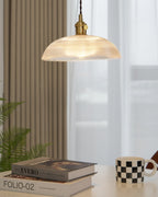 This Clérachic pendant glows above a table set with books and a chequered mug, near a curtained window.