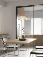 Hanging near glass doors in an open kitchen, this Clérachic pendant sits above a table with a bowl of fruit.