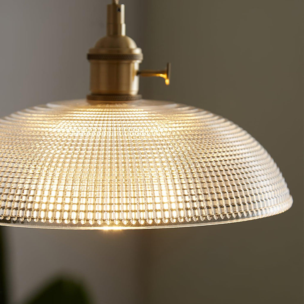 Close-up of the ribbed glass texture on this Clérachic pendant, lit from within, brass fitting visible above.