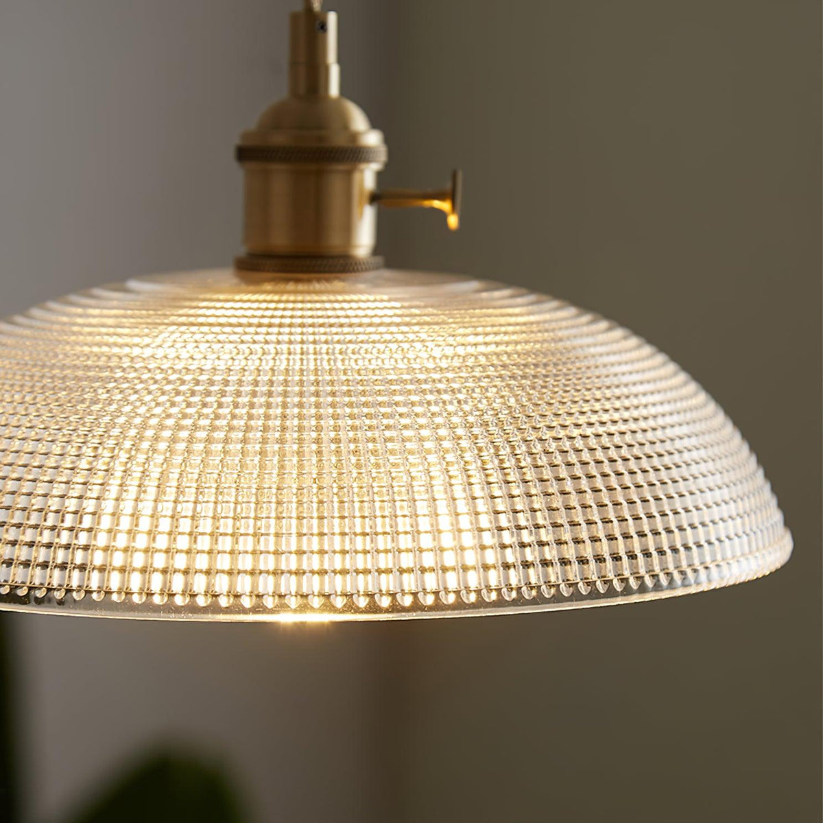 Close-up of the ribbed glass texture on this Clérachic pendant, lit from within, brass fitting visible above.