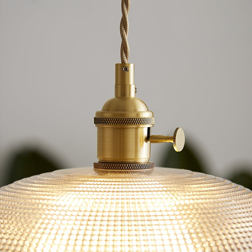 Close view of the brass socket and fitting atop the lit ribbed glass shade of this Clérachic pendant.