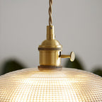 Close view of the brass socket and fitting atop the lit ribbed glass shade of this Clérachic pendant.