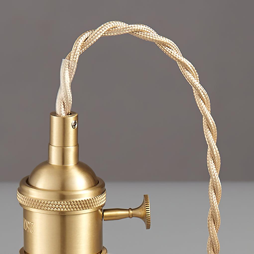 Close-up of the twisted brass cord and socket cap on this Clérachic pendant, against a plain grey backdrop.