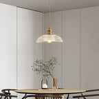 Hanging low over a wood dining table, this Clérachic pendant lights a room with a mirrored wall and greenery.