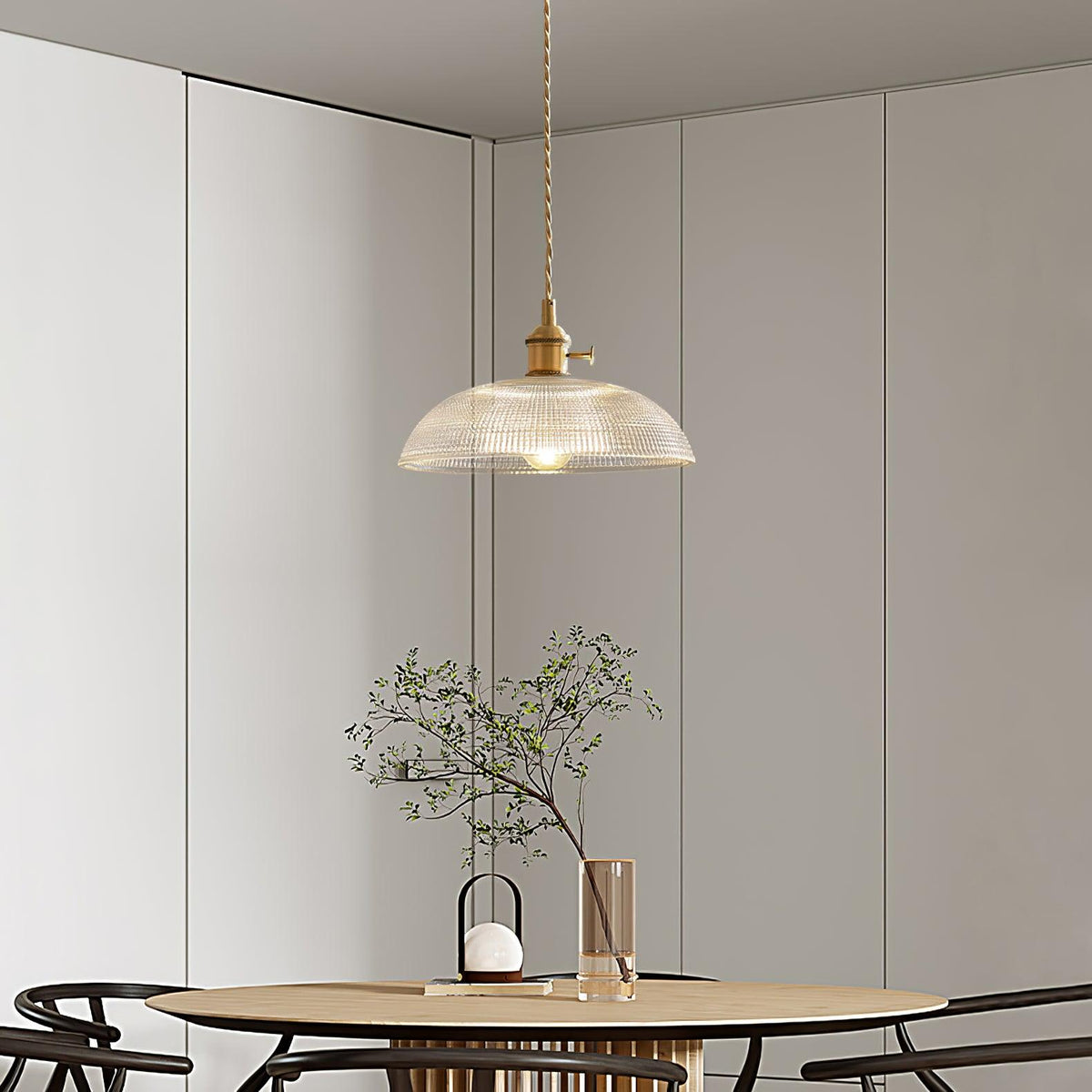Hanging low over a wood dining table, this Clérachic pendant lights a room with a mirrored wall and greenery.