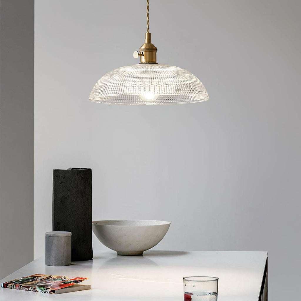 Lit above a white table set with a black vase and a pale stone bowl, this Clérachic pendant glows softly.