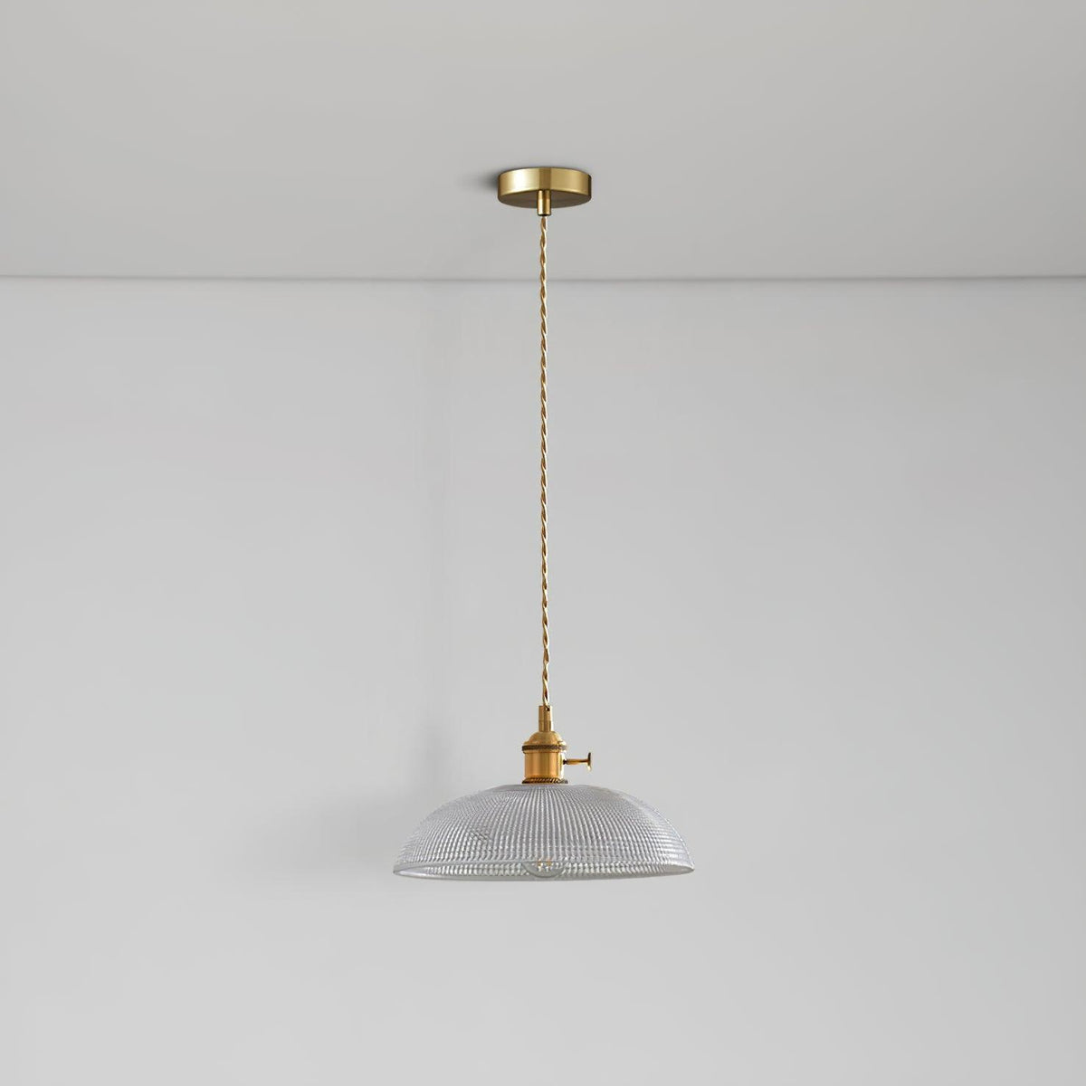 Seen from below, the unlit shade of this Clérachic pendant hangs on a slim brass cord against a white ceiling.