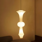 Tall mulberry paper pendant lit warm in an interior