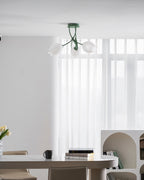 Above a dining table set with tulips, a mug and books, this Clérachic ceiling light in green hangs unlit.