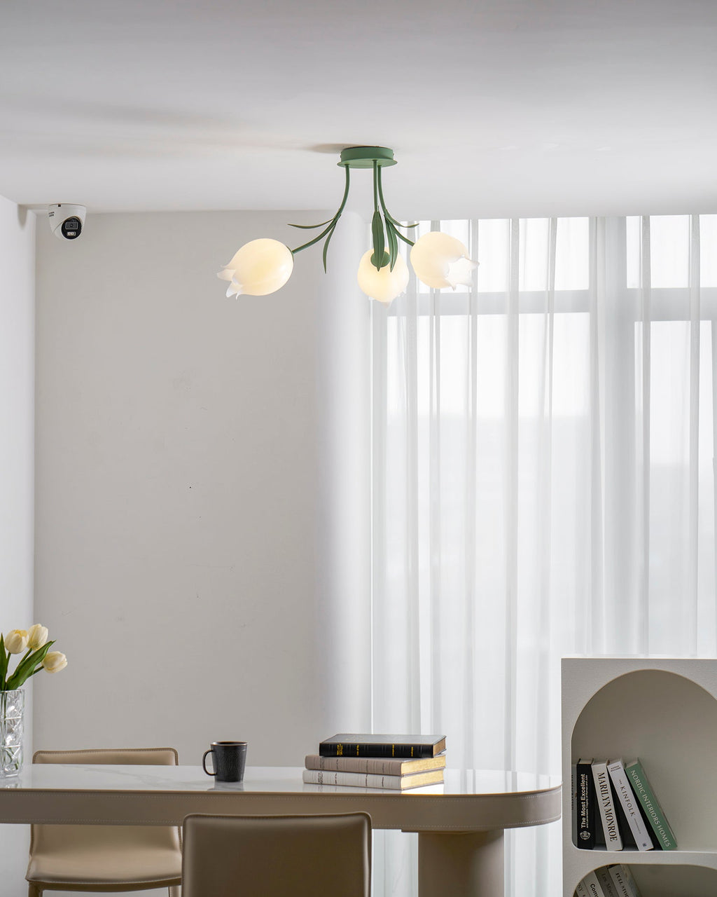 Above a dining table, this Clérachic ceiling light in green hangs unlit with two of its shades clearly visible.
