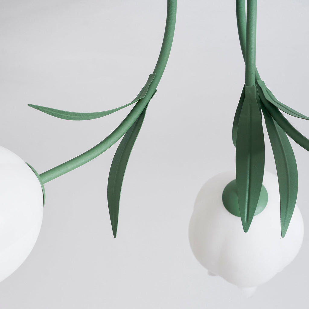 Close view of two stems and leaves on this Clérachic ceiling light in green, converging near the ceiling mount.
