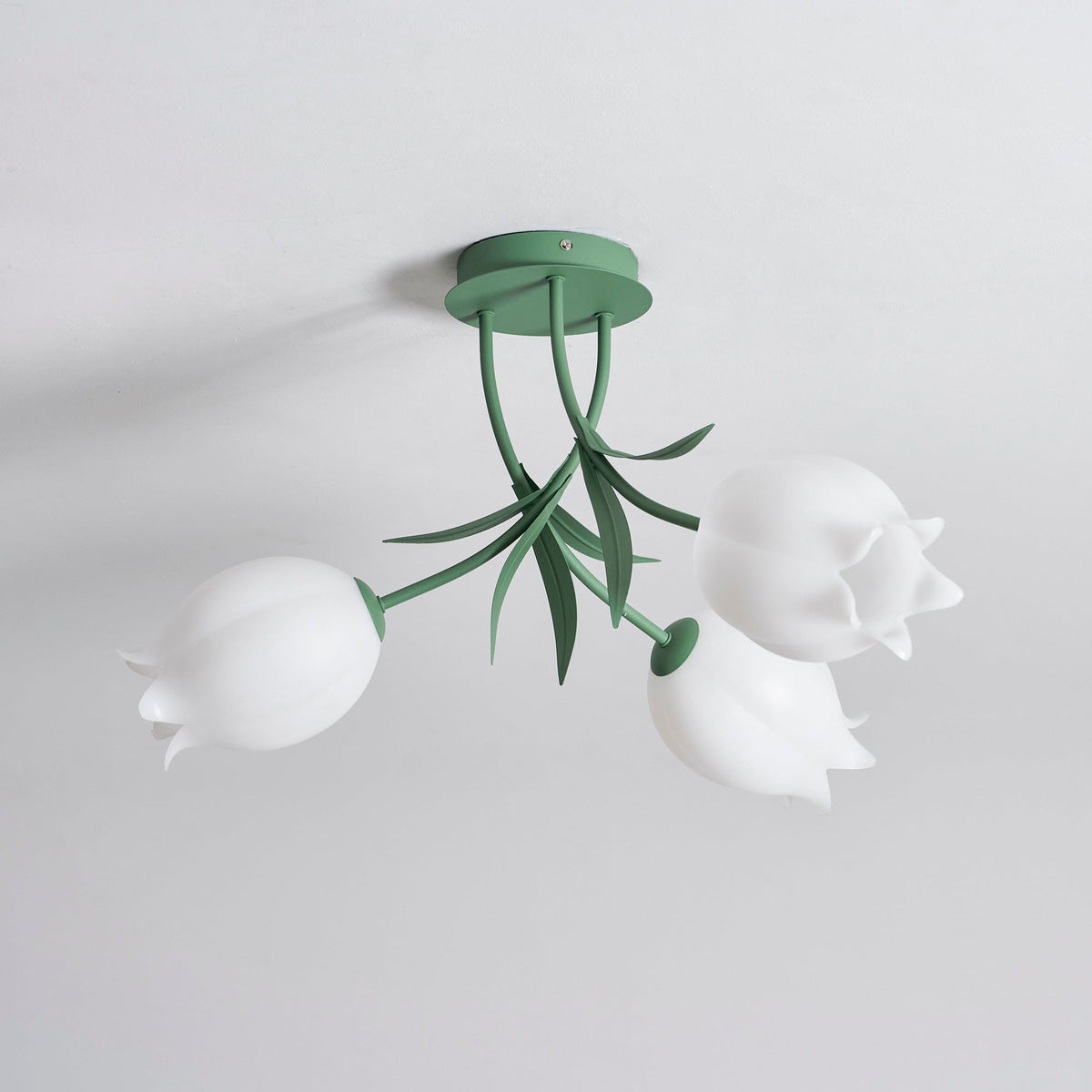 Shown at an angle on a plain background, this Clérachic ceiling light in green displays its three unlit shades.